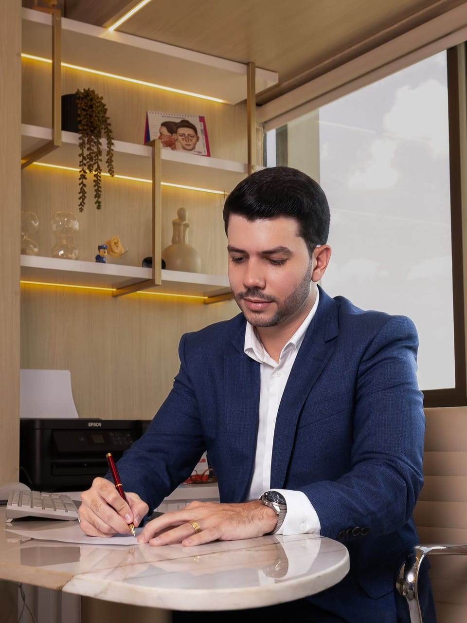 Dr. Giovanni Henrique escrevendo à mesa no consultório